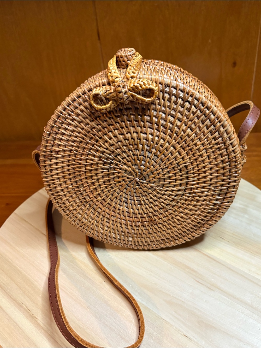 round hand-woven rattan crossbody bag featuring a charming woven bow